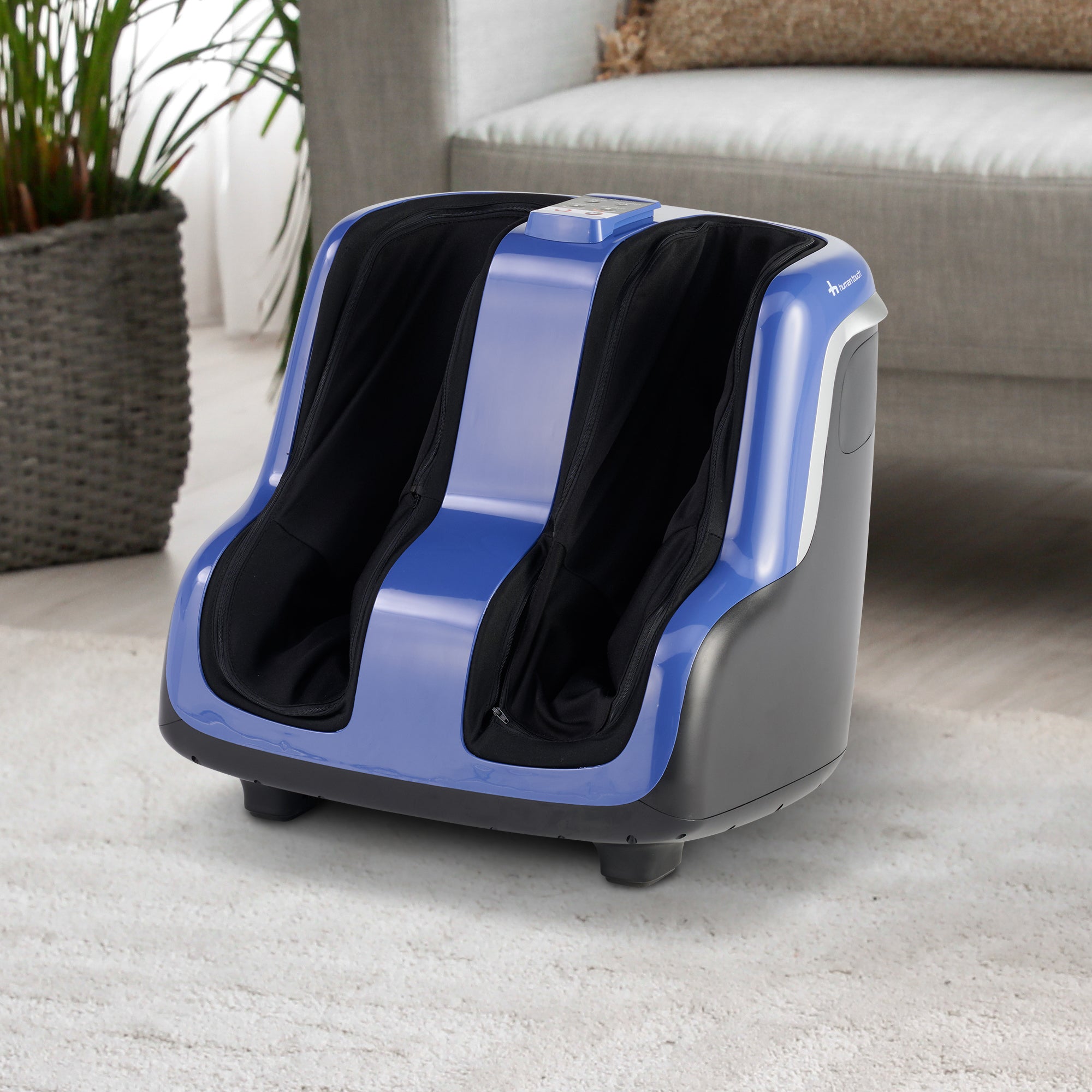 Reflex SOL Plus foot and calf massager with blue accents and black massage chambers shown on light carpet near sofa