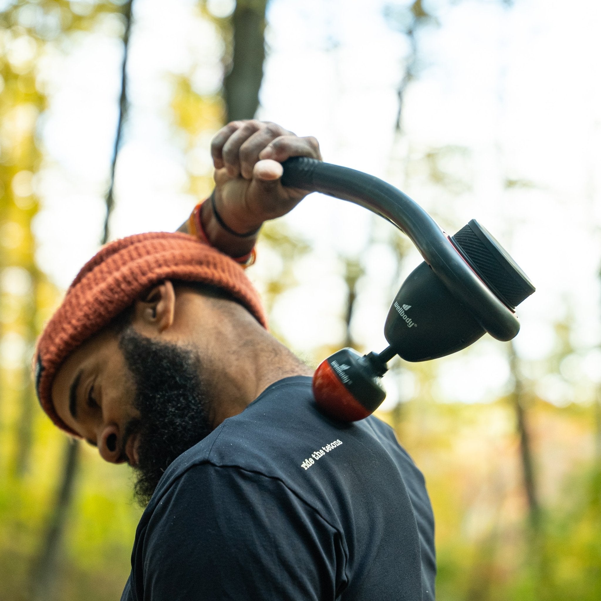 Person holding a massage gun in a forest setting